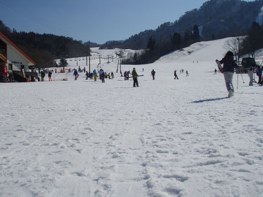 一面雪が積もって真っ白なゲレンデでスキーやスノボを楽しむ人達の写真