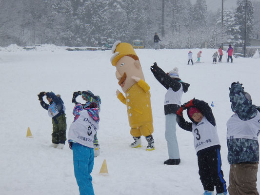 雪が降る中で準備体操をしているレルヒさんと6人の子供たちの写真