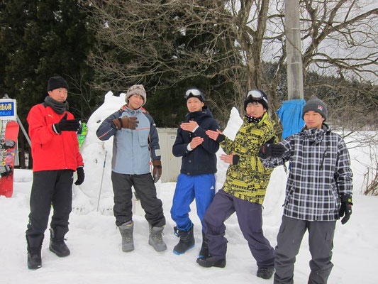 雪だるまの前に立ってポーズを決めている5人の男子学生の写真