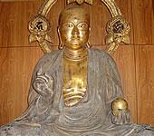 円形の光背のある桂材で彫られた地蔵菩薩坐像の写真