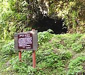 洞窟の入口の左側手前に立て看板が設置されている室谷洞窟の写真