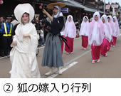 白無垢姿の花嫁さんを先頭に、袴姿の男性、赤い着物に白い衣装をきた人たちが並んで道路を歩いている写真